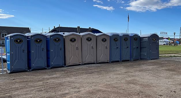 A row of blue and beige portable toilets, available for rent.