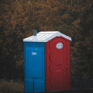 A red and blue portable toilet with white roof.